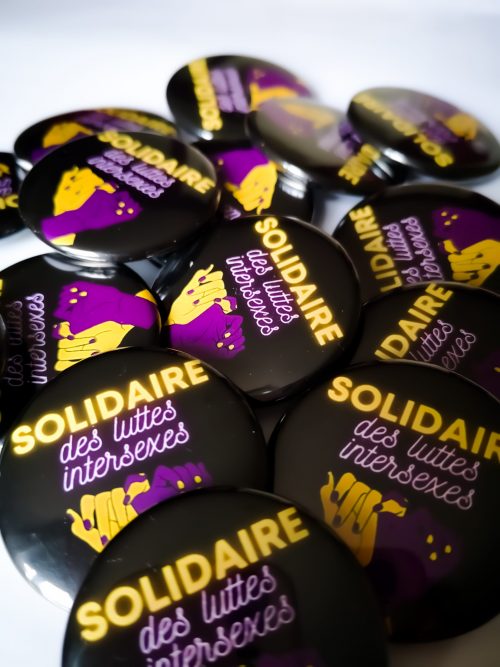 fond noir, deux mains jaunes et violettes entrelacées, slogan "solidaire des luttes intersexes"